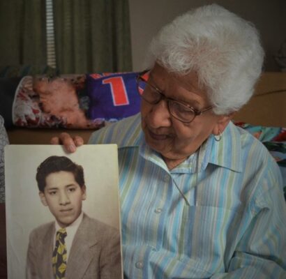 Mary Munos Ramirez (John's sister) with a photo of John.