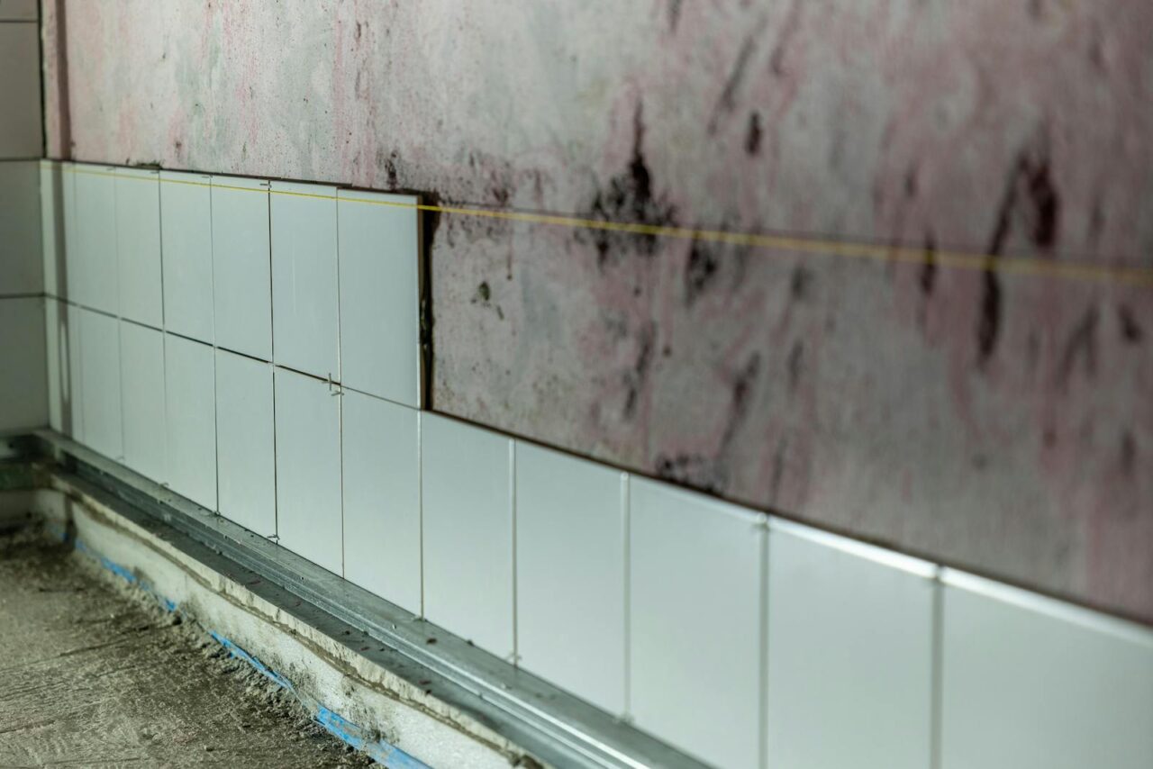 Close-up of partially tiled wall in a construction area, showcasing incomplete renovation work.