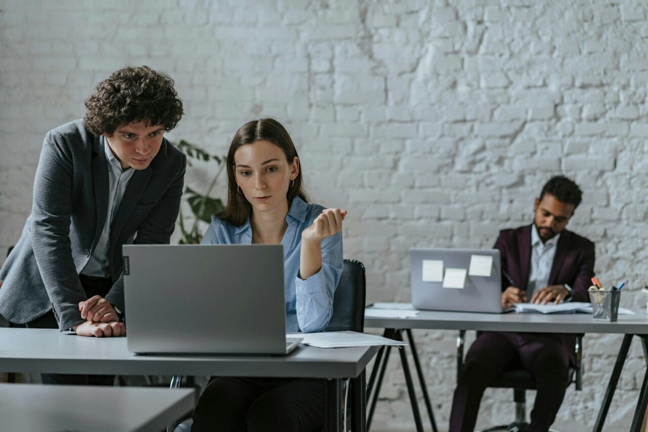 Two colleagues collaborating on a laptop in office.