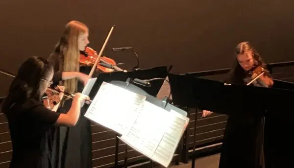 QC Youth Symphony Orchestra members Haven O'Brian, left, Bethany Priaulx and Elise Brock playing at the Putnam Giant Screen Theater Tuesday night (photo by Jonathan Turner).