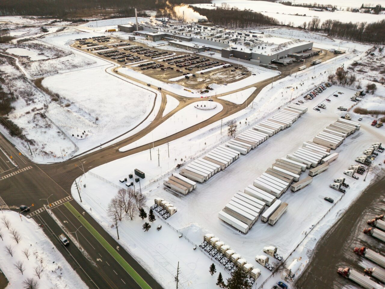 Aerial view of a snowy industrial complex with trucks.