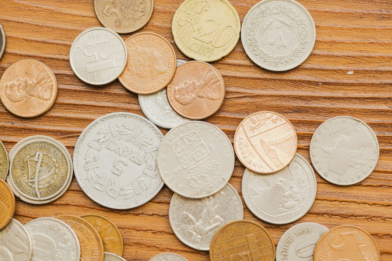 A collection of various coins scattered on a wooden surface.