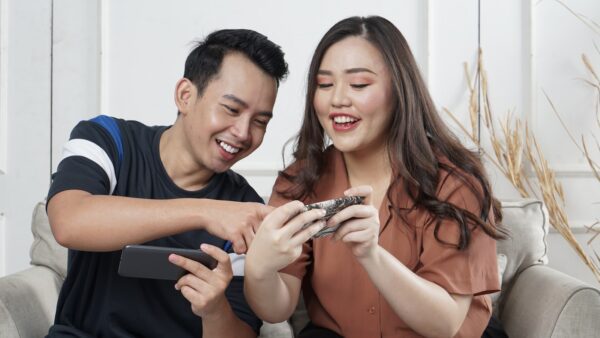 man and woman siting on sofa chair inside room on phone mobile gaming