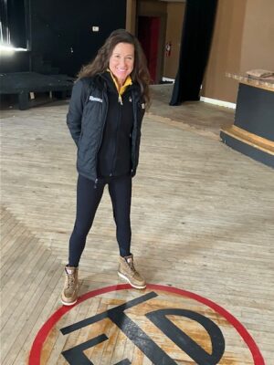 Michelle Russell stood at the building's original floor logo (which stood for East Davenport Turners) in December 2024 (photo by Jonathan Turner).